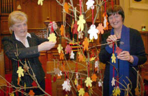 Hazel Loney (left) and Jean Gibson attach figures to the tree symbolising the oneness of the worldwide church.