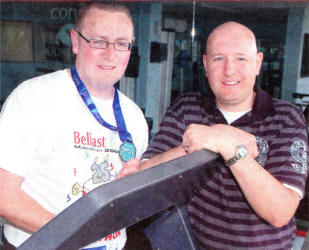 Edward Campbell (left) displays his medal after his recent fundraising run in the Belfast Marathon to friend and colleague Alan Burns in the new Corus Lisburn employees' gym.