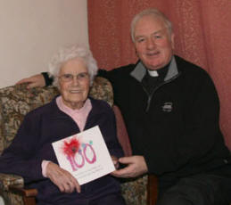 Isabel McArdle pictured with Lisburn Parish Priest, the Very Rev Dermot McCaughan as she displays one of her many 100th Birthday Cards.