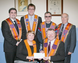 Alicia Dickson of Lower Iveagh Cultural and Heritage Committee is pictured presenting two cheques to Bro Drew Nelson (Secretary - Grand Orange Lodge, Ireland) for forwarding to the Lord Enniskillen Memorial Orphan Society. Looking on are Lower Iveagh Cultural and Heritage Committee members L to R: (back row) Bro Dr Jonathan Mattison (Deputy District Master), Bro Edward Hanna, Bro David Hobson (District Secretary) and Bro Eric Jess (Worshipful District Master).