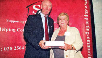Ann Watson receiving her award from Colm McCaughley, the Housing Executive's Director of Housing and Regeneration.