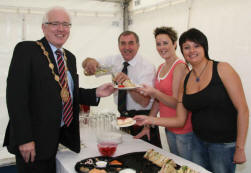 Maurice Dickson (Ballydonaghy Pipe Band), Joanne Ussher and Victoria Lappin pictured serving up lunch for Lisburn Mayor, Councillor Allan Ewart at the All Ireland Pipe Band Championships in Lisburn last Saturday (4th July).