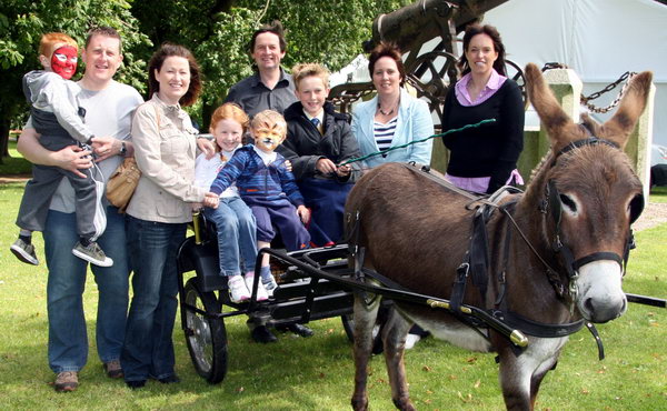 Damien and Aine Ryan look on as their children Tiernan, Caoinhe and Eoin enjoy a free ride on Robert Wallace’s donkey and trap at the Farmer’s Market in Castle Gardens, Lisburn on Saturday 1st August.  Included are Richard Wallace (Robert’s father) and Lisburn City Council’s Jenny Palmer (Economic Development Chairman) and Suzanne Lutton (Regeneration Manager).