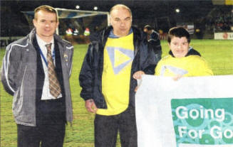 Curtis Todd (right) and his uncle, (centre) fly the flag for Positive Futures at Windsor Park, with support from the IFA's Geoff Wilson.