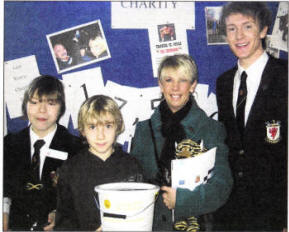 Wallace Year 8 pupil Daniel Nash and Head Boy Richard Johnston with Jamie Hewitt from Ballynahinch Primary and his Mum Karen with the Northern Ireland Cancer Fund for Children charity raffle of a signed copy of Harry Potter and the Half Blood Prince.