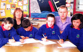 Derriaghy PS Principal, Mrs Topping, and P6/7 teacher, Mr Watson, look on as pupils write letters to the Department of Education and the SEELB to stop the closure of their school.
	