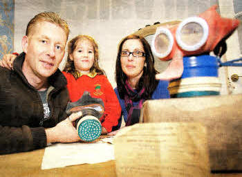 Tommy Haydock and Gina Everett, with their daughter Maddison, examine old World War II gas masks they found in the attic of their home at Kesh Road, Lisburn. US3711-582cd