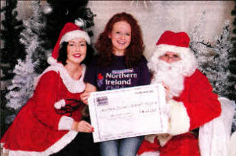 Emma Doone dresses as Mrs Claus and Santa presents Naimh McGlichey from NI Children's Hospice with a cheque from 4ever Photo Studio.