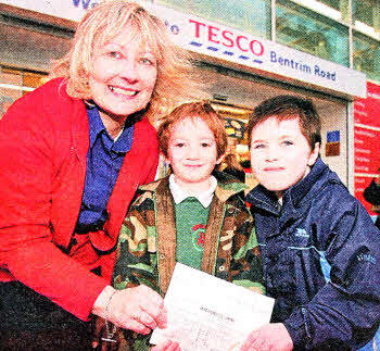 Anne Broome, community champion at Tesco, presents a cheque to Paul Barnes and Thomas McCinton, from the Lisburn branch of Autism NI, which was raised during a bag pack at the Bentrim Road store. US4811-530cd