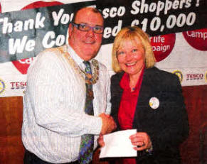 The president of the Rotary Club of Lisburn, Trevor Stewart, presents a cheque to Anne Broome, Community Champion at Tesco Bentrim Road, for CLIC Sargent.