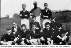 Culcavey's Distillery Football Team photograph taken c. 1920s with Puddledock row and Grey Row in background.