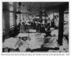 Part of the top room used for printing and cutting. John Hamilton is the man on the right with the stick. (W.P.)