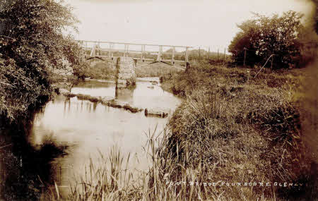 An early 20th century postcard depicting the original footbridge across the river in the townand of Ballymoneymore, outside Glenavy. The stepping stones can also be seen in the picture. 