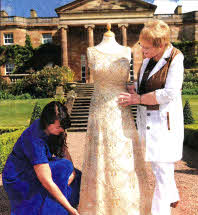 Local dress designer Lizzie Agnew and Patsy Browne, Embroiders Guild NI admire one of the Queen's Dresses, worn by Her Majesty at the State Opening of Parliament in 1979, on display at