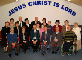 Pictured at the official opening of the new Magheraknock Mission Hall last Saturday afternoon (11th November) is L to R: Trustees (seated) - Parker Williamson, Glenny Waddell, James Carlisle, Sam Sommerville, Ronnie Douglas and Mark Gibson. (back row) Babs Fox, Ethne Douglas, Kirsty Waddell, Alex Reid, Margaret Reid, Bill and Anne Reid with children Lee-Anne, Petra and Douglas, Sylvia Reid, Joan Fletcher and Marella Marshall.