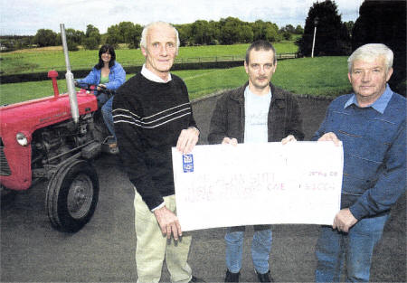 Alan Stitt (centre4 receives a cheque for �3,100 from Michael Timmons and Alan Ross with Alan's wife in the background on the Massey Ferguson which was used in the charity tractor run US3708-402PM Pic by Paul Murphy
