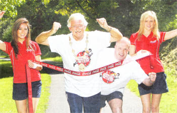 The Mayor of Lisburn, Councillor Ronnie Crawford and Councillor James Tinsley who will both be taking part in this year's Lisburn Half Marathon, 10K Road Race and 3K Fun Run, practise passing the finishing line. Cheering them on are (I-r): Judith Wilson and Christine Jackson representing event sponsor Coca Cola