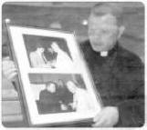 Father Fergal McGarry from St Colman's Church looks at pictures of himself with Pope John Paul. The pictures were taken 20 years apart. US14450CL Picture by: Colm Lenaghon