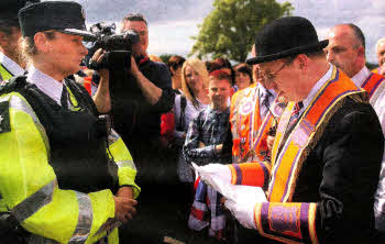 A letter of protest about the Parades Commission determination is read by the Orange Order to the PSNI at the field. US2912.163A0