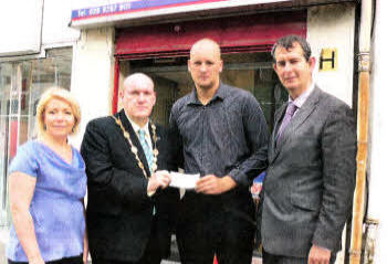 The Mayor, Alderman William Leathem, presents a cheque from the people of Lisburn to Sandis Balins who accepted it on behalf of Ksenija's mother. Included are Mary Magee of the Ulster Star and MLA Edwin Poots